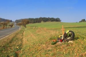 Teen driver death with religious cross on the side of a road in a field