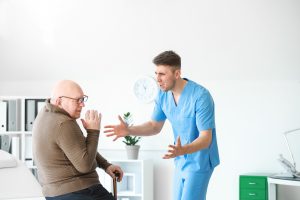 elder neglect and abuse - a male nurse yelling at an elderly person